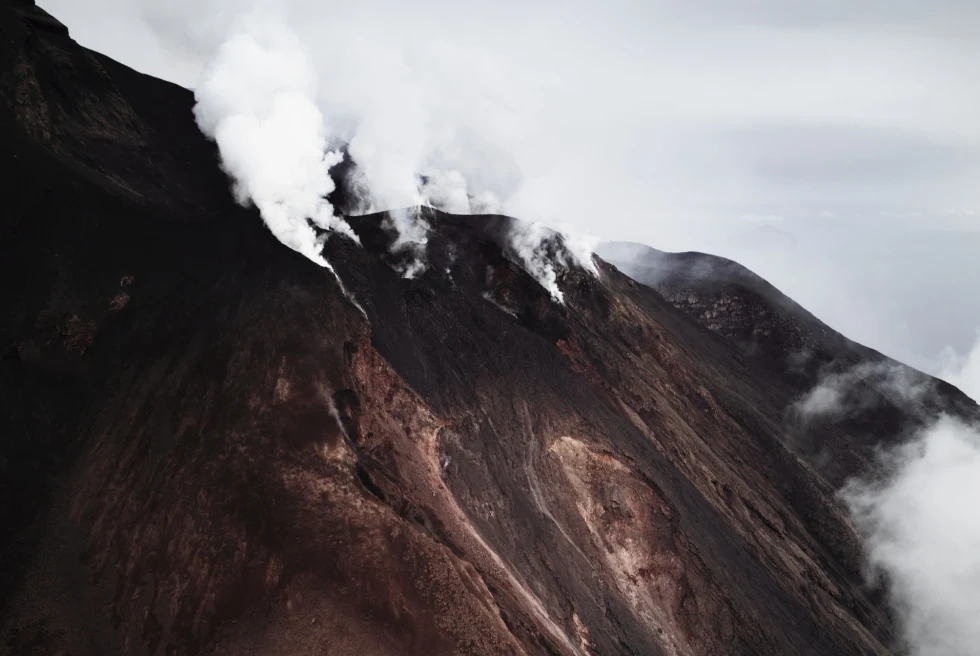A brown volcano with clouds 