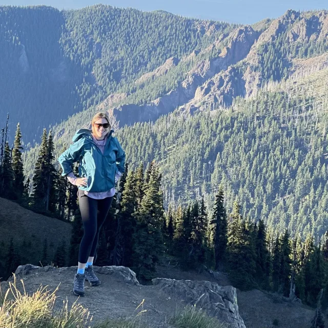 Travel advisor Rachel Webb in a blue puffer jacket standing on a mountain trail