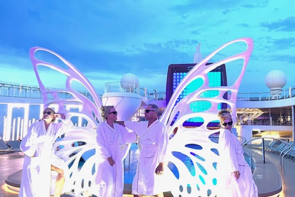 couple stand in bathrobes on cruise deck with butterfly sculpture