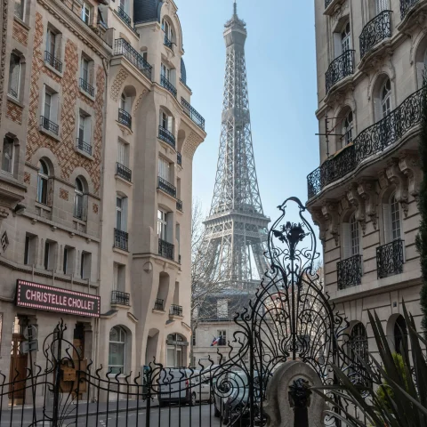 A low angled view of the Eiffel Tower between two buildings.
