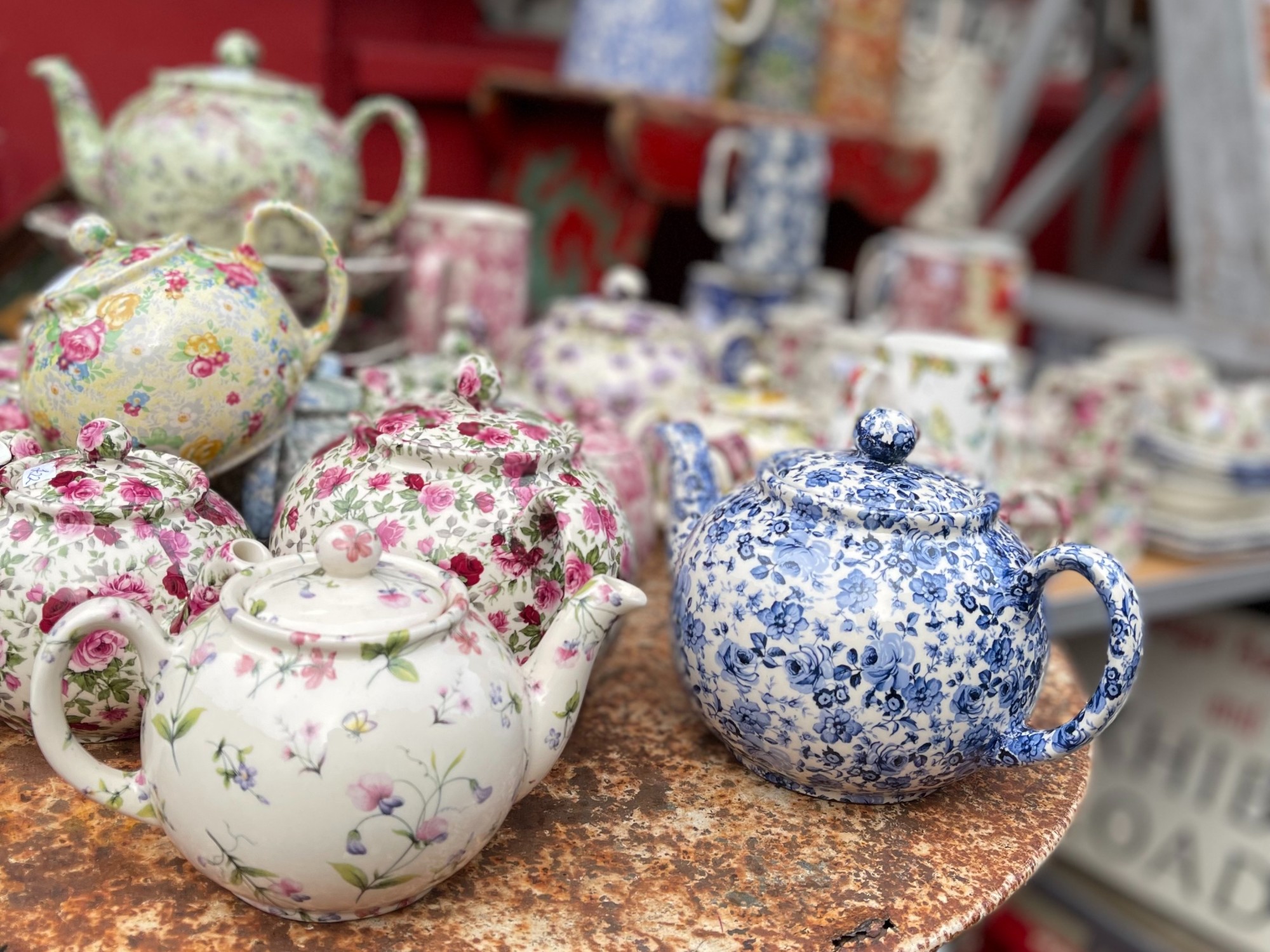 Colorful floral tea pots on a round table.