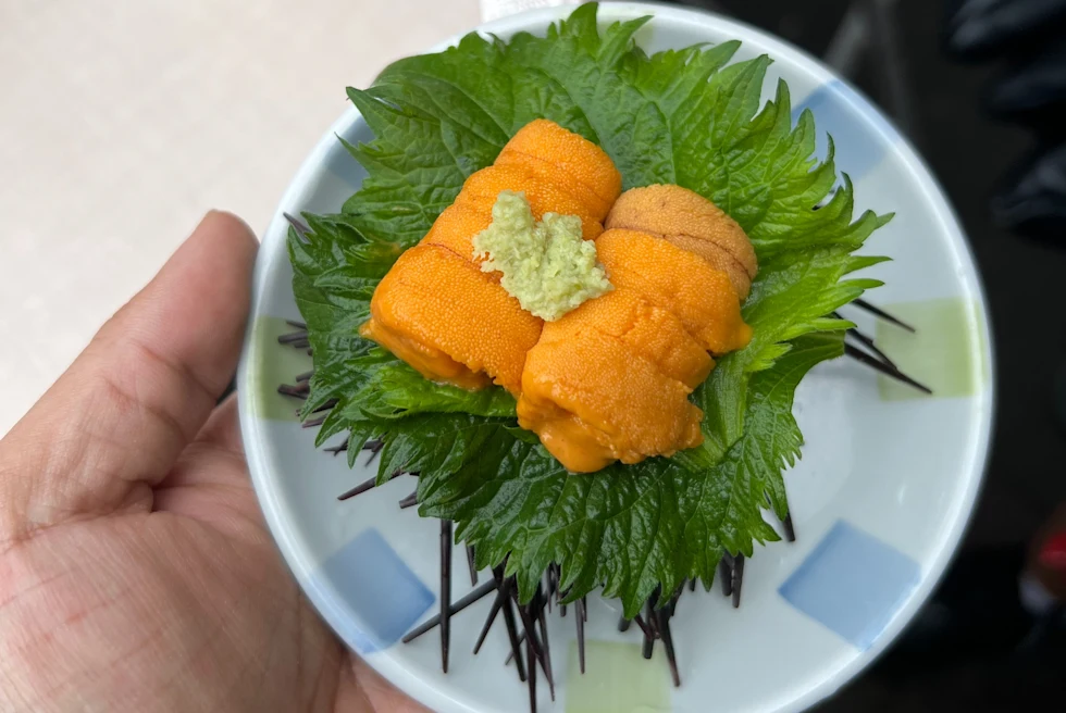 A man holding a small bowl of Japanese food.