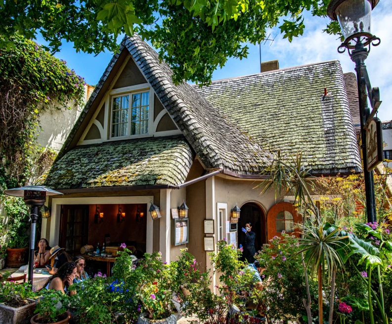 quaint restaurant in a thatched cottage with trees and foliage surrounding a busy patio