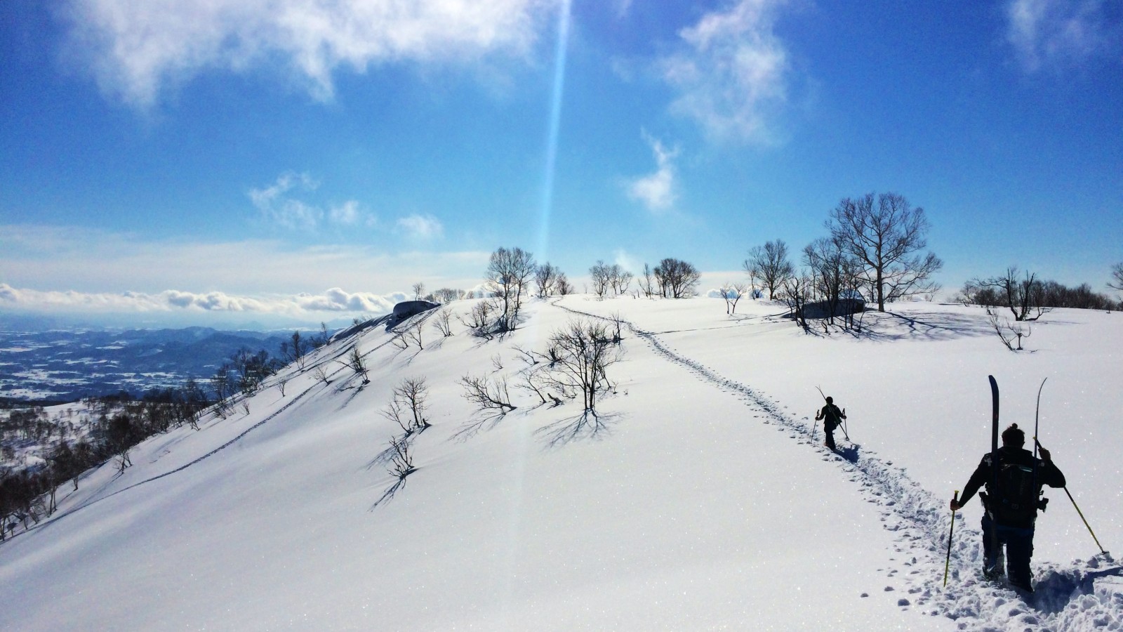 People hiking with skis on snow-covered mountain during daytime