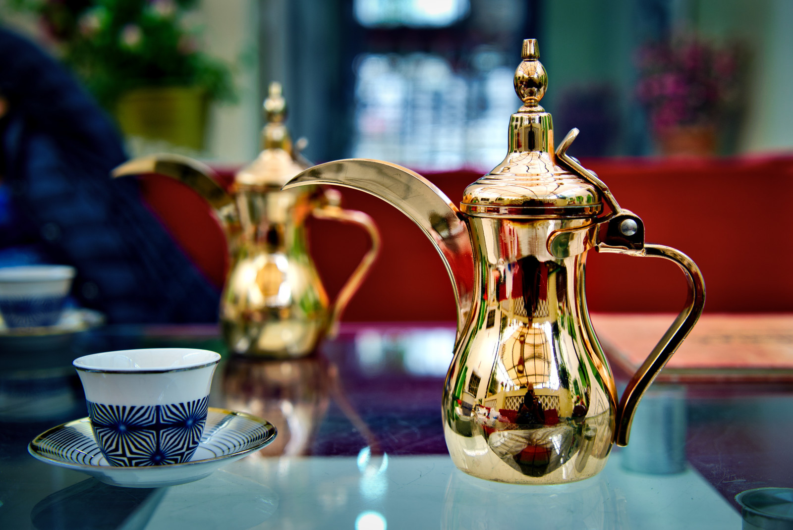 Gold pot of tea and blue and white cup on a glass table in Dubai
