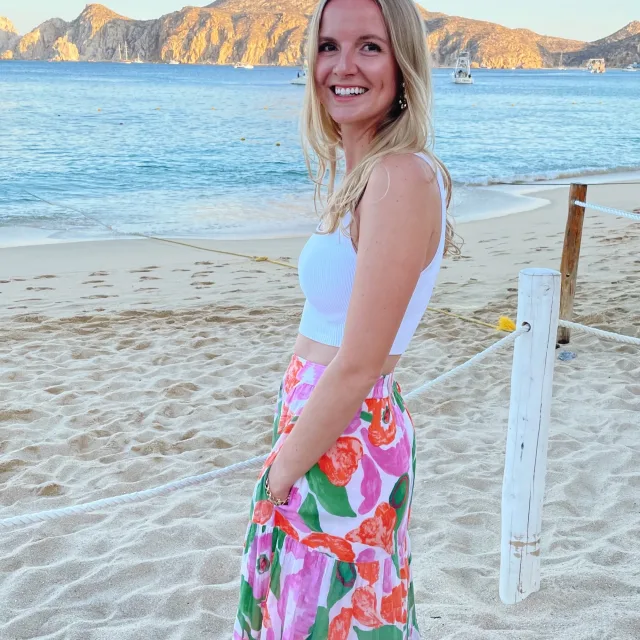 Travel Advisor Isabelle Paradis wears a colorful pink, orange and green maxi skirt on a sandy island beach