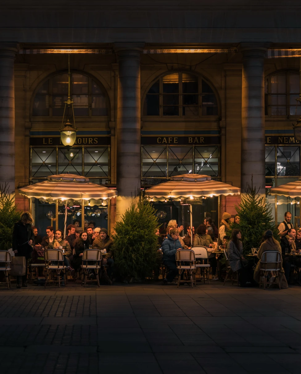 Best Paris restaurants at night with four lit umbrellas.