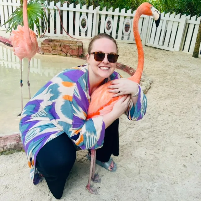 Picture of Sami hugging a flamingo during the daytime.