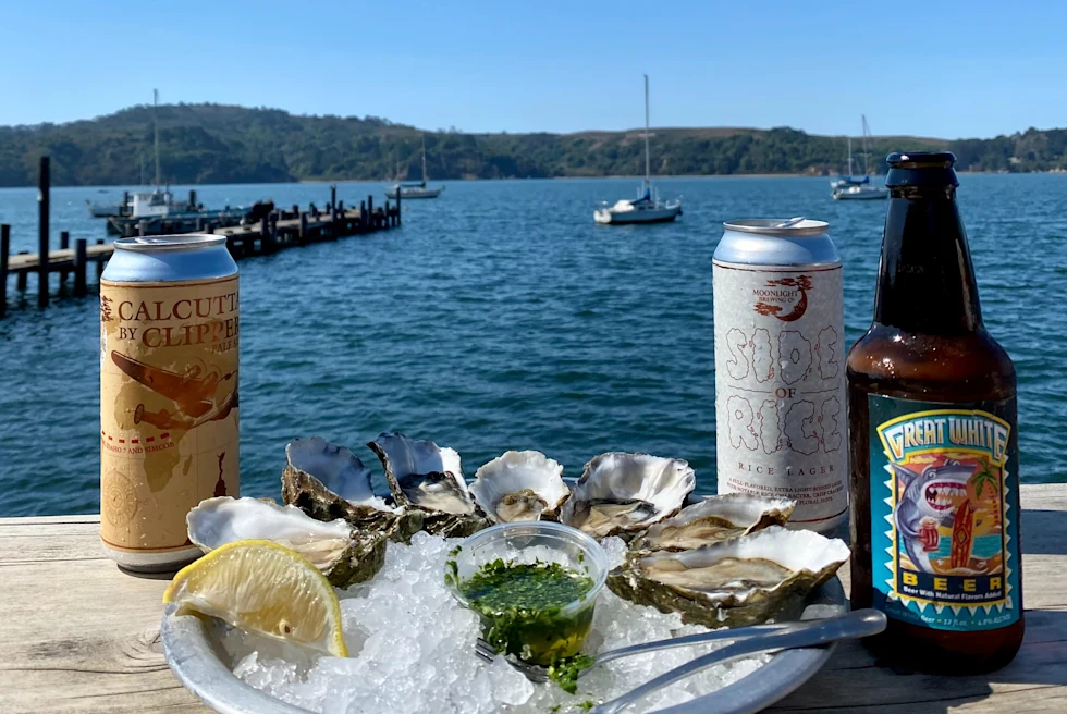 plate with oysters and beers on a wooden ledge overlooking the water