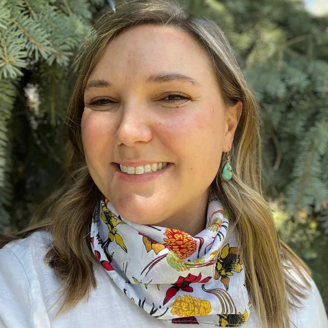 Travel Advisor Ashley Garber in a colorful bandana and a green tree in the back.