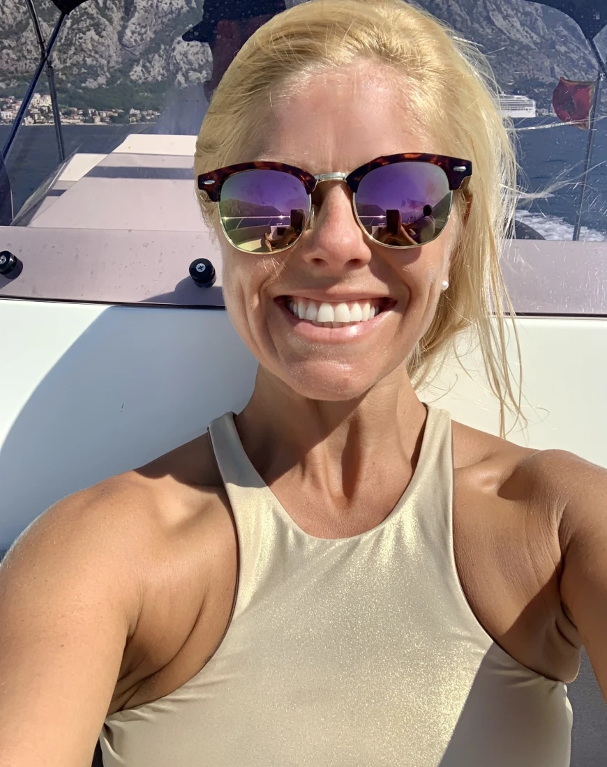 a woman in a gold halter top and sunglasses smiles