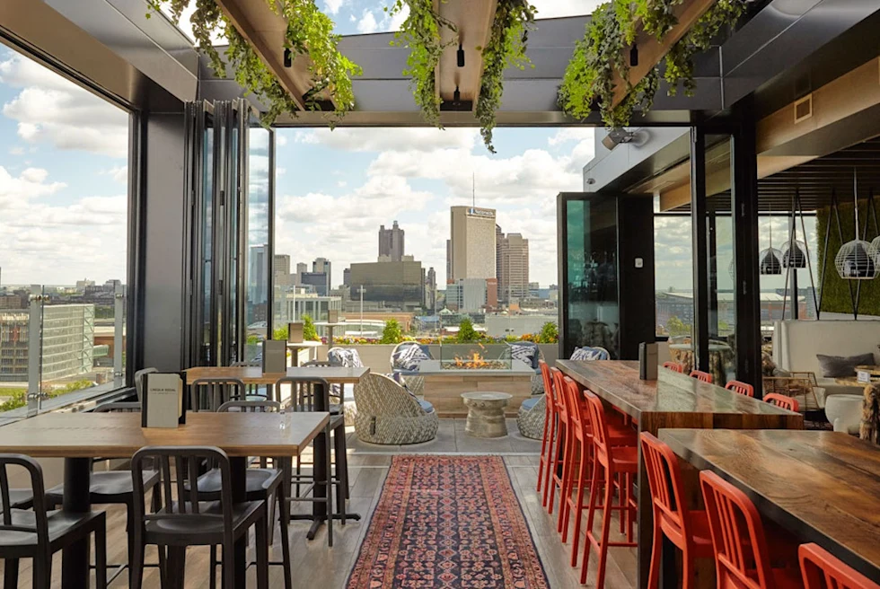 An empty restaurant with large glass windows showing the city skyline.