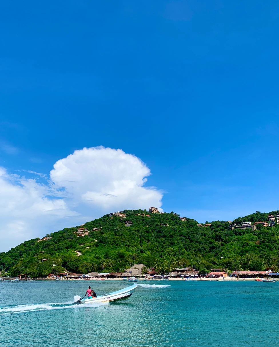 small boat cruising through clear blue waters with island scene in the background 