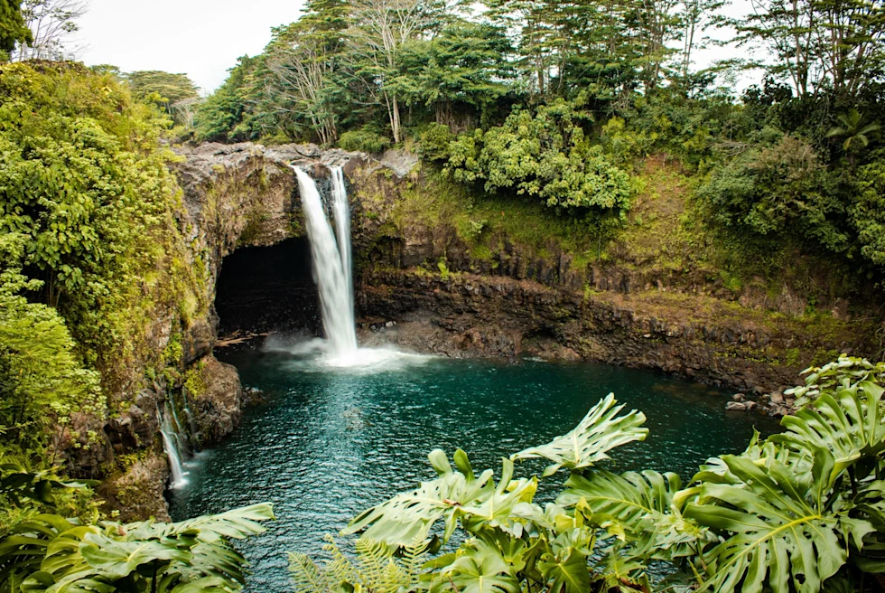 rocky waterfall into lagoon surrounded by green foliage