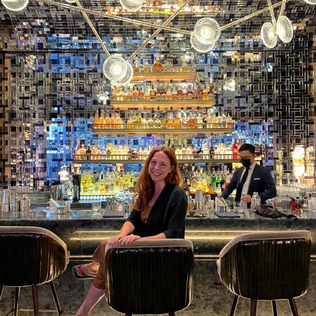 Travel advisor Rachel Kroft sitting in front of a well-stocked bar.