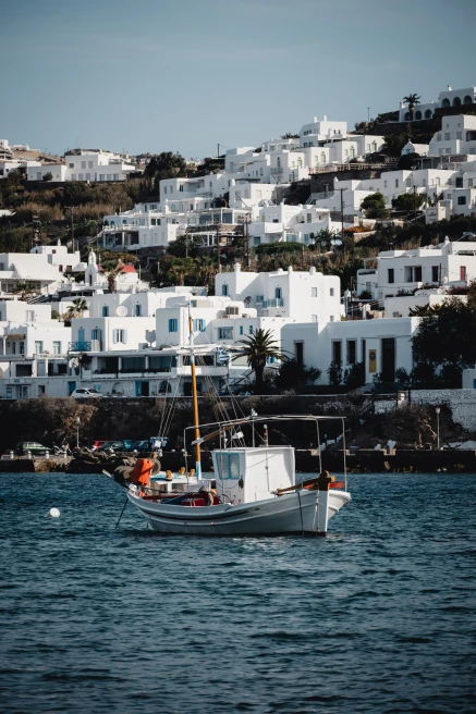 White boat in body of water with white houses in the background during daytime
