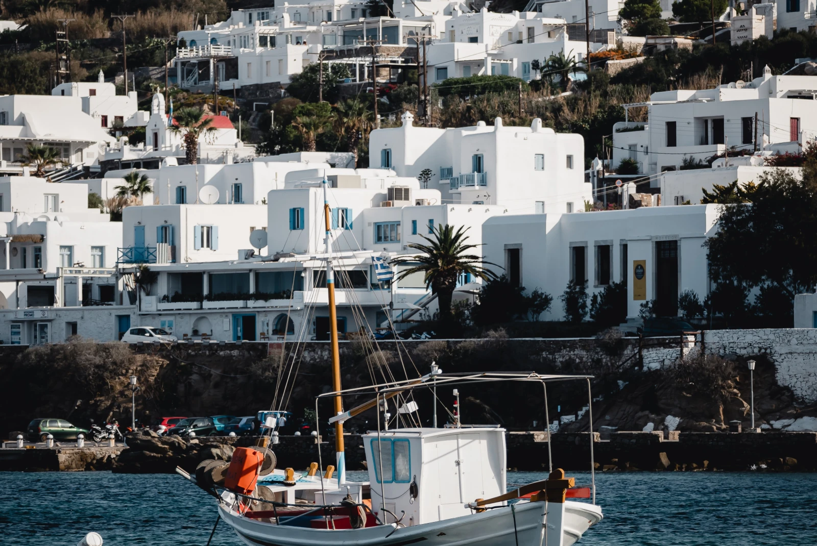 White boat in body of water with white houses in the background during daytime