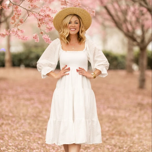 Travel Advisor Caroline Bernthal in a white dress, brown hat posing among cherry blossom trees.