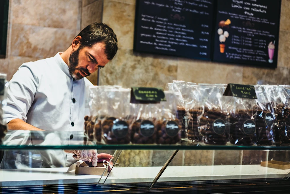 A man boxing up pastries in Spain.