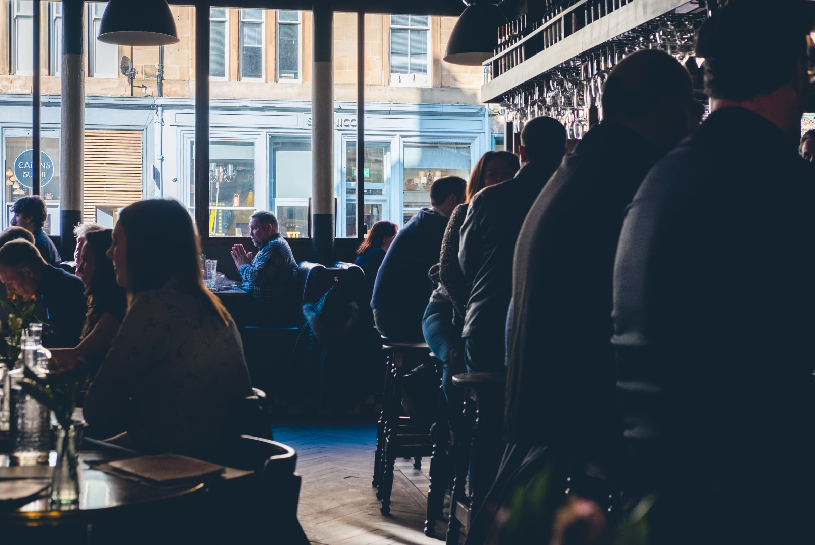 People sitting at tables and at the bar at pub in Glasgow