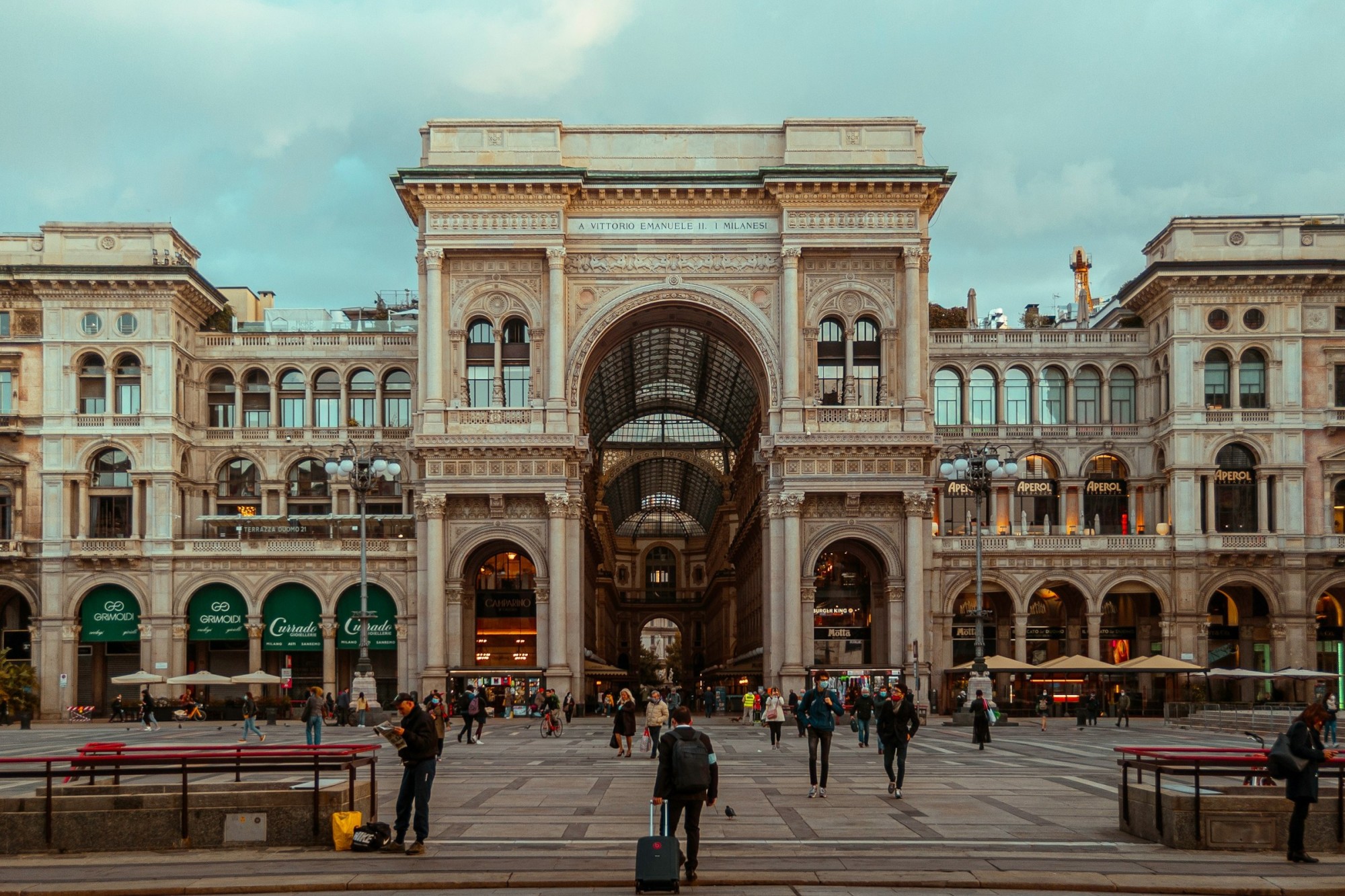 Dozens of locals and travelers walk before the historic Galleria Vittorio Emanuelle II in Milan, Italy