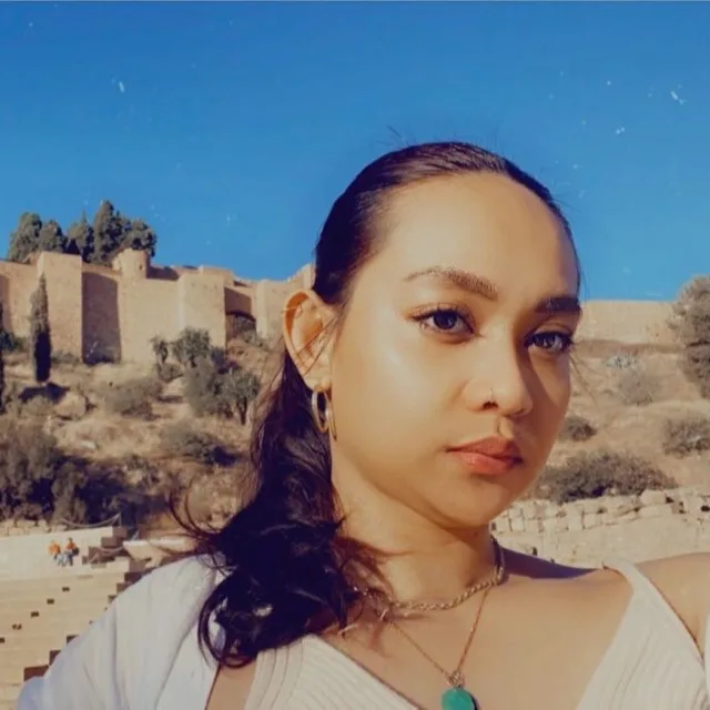 Travel Advisor Nikka Gamalinda in a white shirt and ponytail with ruins in the background.