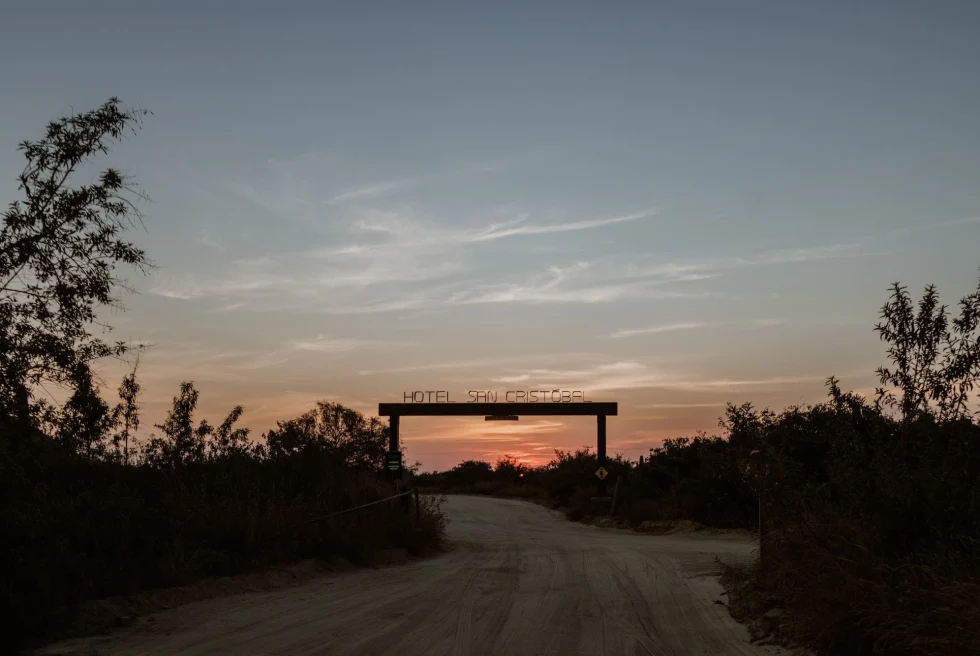 entrance to a hotel on a dirt road at sunset