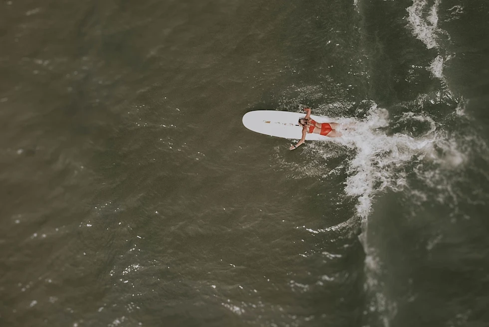 A girl lying on a ski board on a beach.