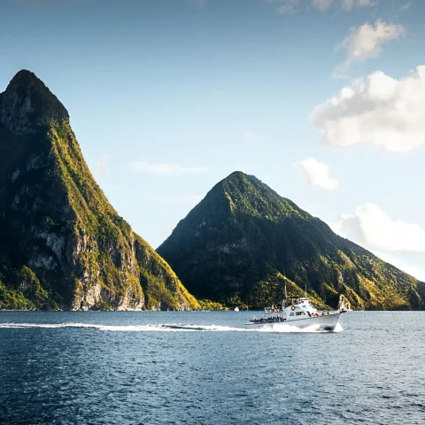 the twin volcanic peaks of Piton's Peak across the bay with a tour boat taking travelers around the island (photo by Daniel Öberg)