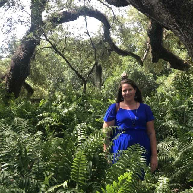 travel advisor Casey Stone Philbrick in a blue dress amid lush greenery