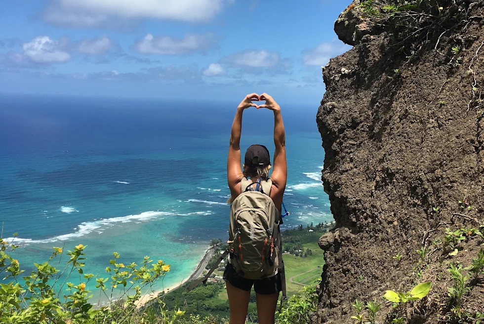 Woman standing on mountain with ocean in background during daytime
