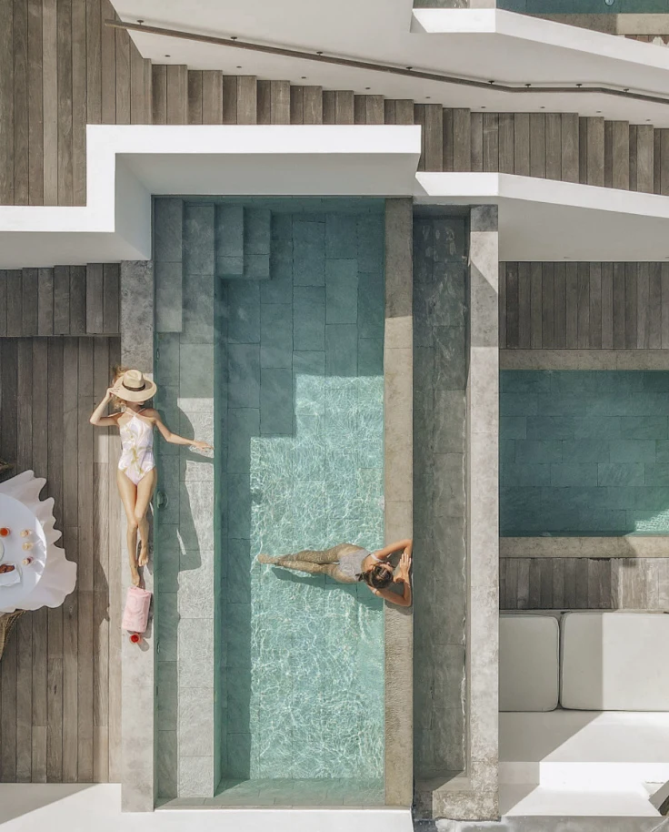 Two women lounging in private pool of their Greek-inspired white villa in St. Barths.