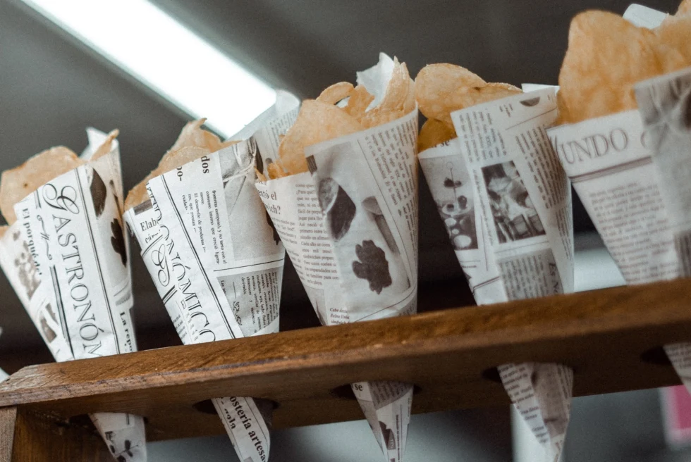 a row of potato chips wrapped in newspaper cones