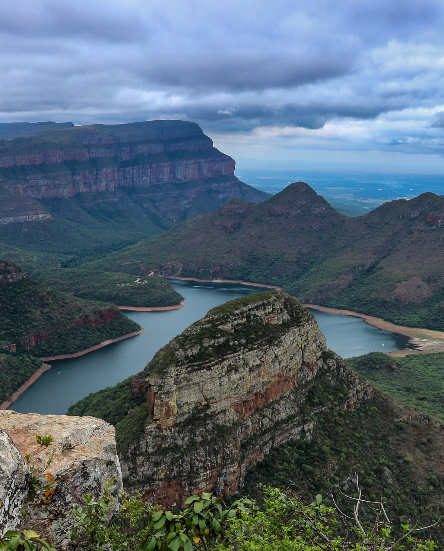 Body of water surrounded by mountains with clouds in the sky during daytime