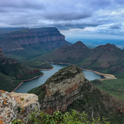 Body of water surrounded by mountains with clouds in the sky during daytime