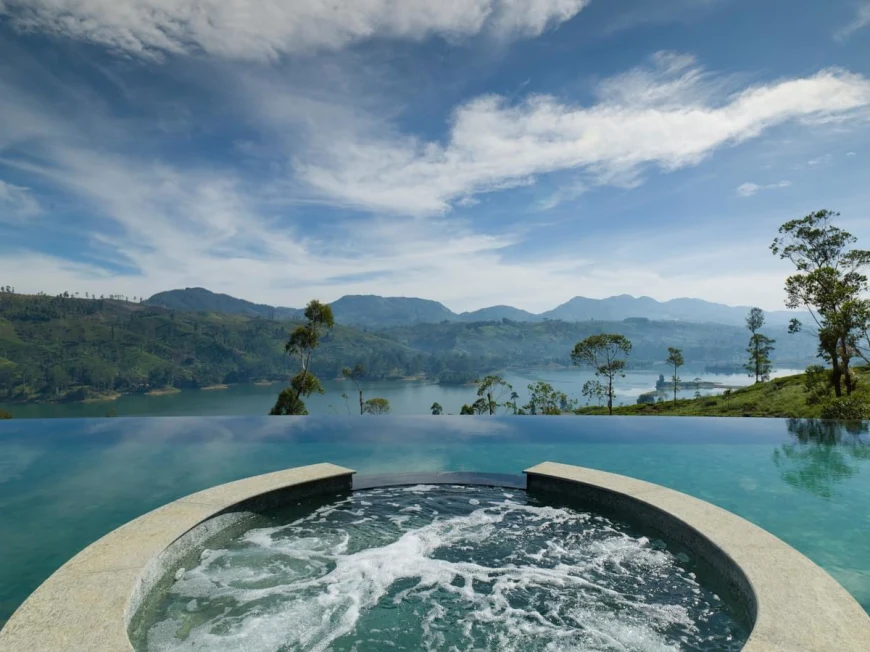 a hot tub within an infinity pool overlooking a lake surrounded by greenery