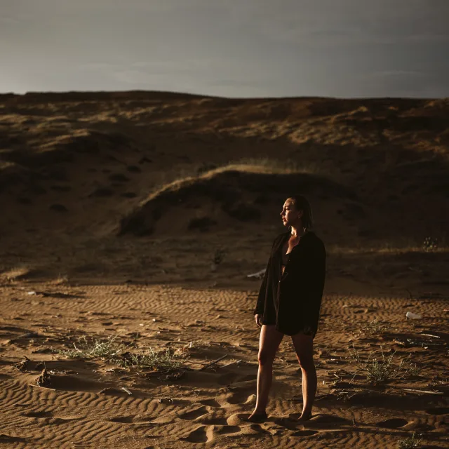 woman wearing black shirt standing outside with hills in the background