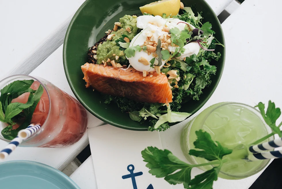 Salmon salad with sweet raspberry drink on white table at beachside restaurant.