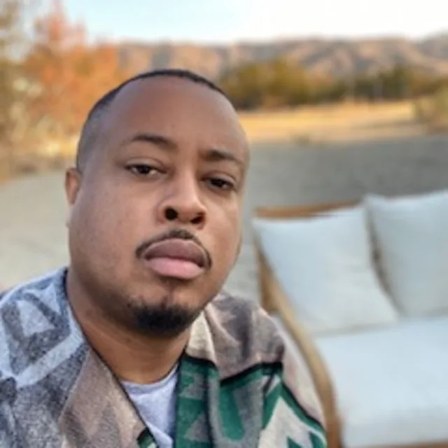 Man poses for the camera in front of mountain background