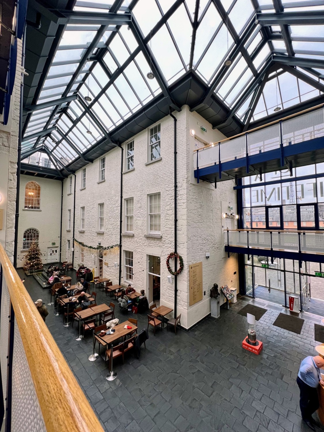 A top-down view of one of the dining areas at the Silk Road Cafe in the Chester Beatty Library complete with tiled flooring, white brick walls and a glass ceiling.