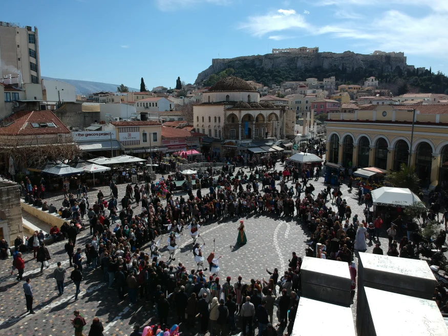 A group of people standing in a circle in a plaza in Monastiraki neighborhood of Athens. 