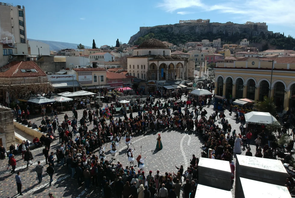 A group of people standing in a circle in a plaza in Monastiraki neighborhood of Athens. 