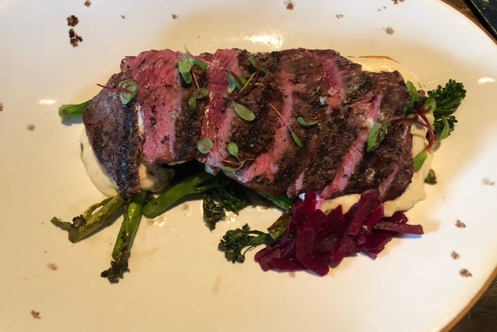Sliced steak over vegetables on a white plate