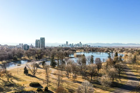 aerial view of a park with trees where people like to spend weekends in Denver, and the city skyline with mountains in the background