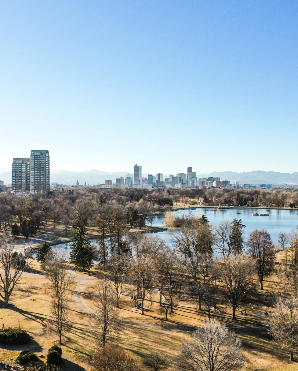 aerial view of a park with trees where people like to spend weekends in Denver, and the city skyline with mountains in the background
