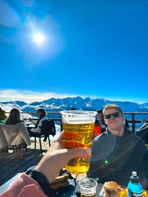 woman cheers beer to man on snow mountain cafe