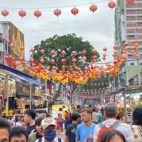 A busy street filled with people and red lanterns in Kuala Lumpur.