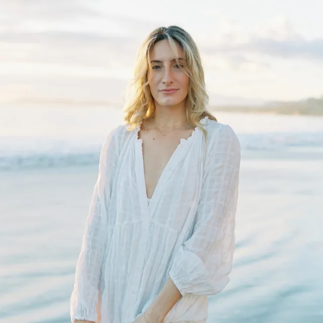 Travel Advisor Olivia McGovern in a white dress standing in front of the ocean.