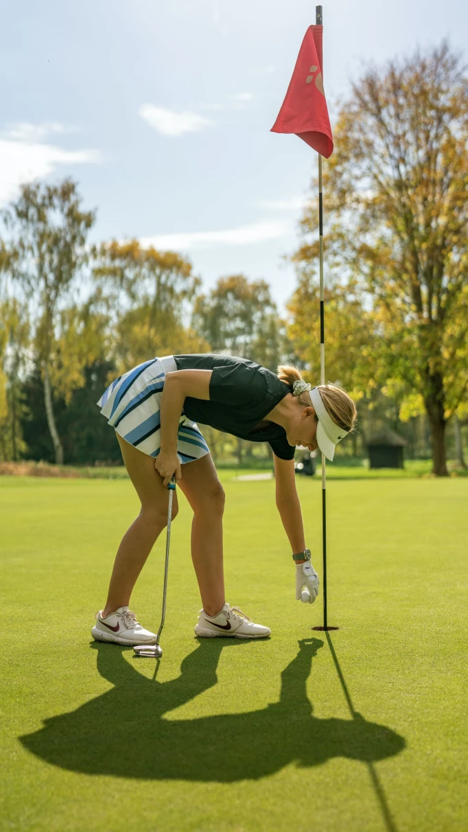 A picture of a woman putting a golf ball on the course.