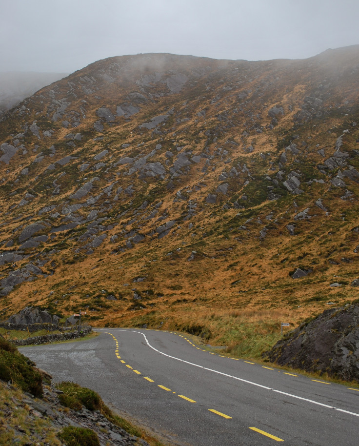 road next to mountain with cloudy skies